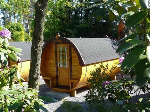 Ferienpark Auf dem Simpel - Schlaf-Fass 1 في سولتو: منزل كلب خشبي صغير مع سقف رمادي