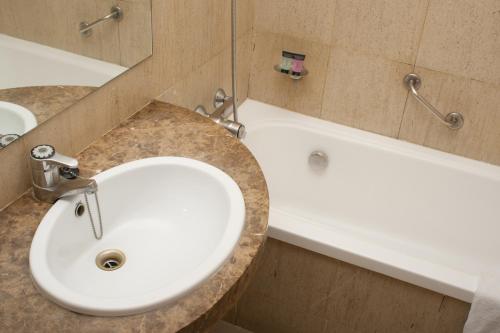 La salle de bains est pourvue d'un lavabo blanc et d'une baignoire. dans l'établissement Hotel Abbot, à Barcelone