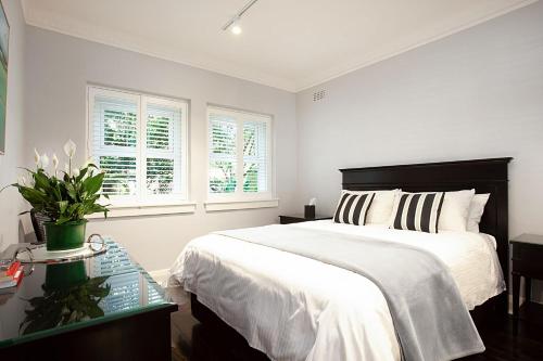 a white bedroom with a large bed and windows at Bayside Retreat in Sydney