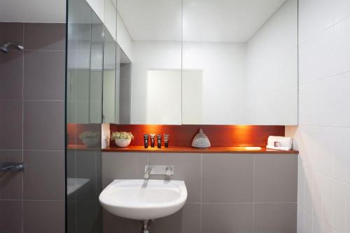 a white bathroom with a sink and a mirror at Bellevue Beauty in Sydney