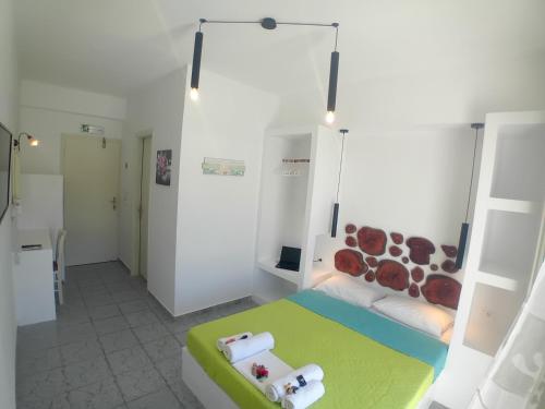 een witte kamer met een bed met een groen en wit bed. bij Nikolas ios Village in Ios Chora