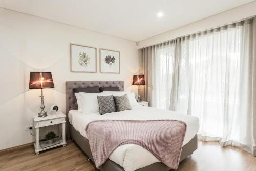 a white bedroom with a large bed and a window at Blissful Bream in Sydney