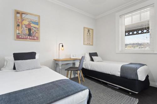 a hotel room with two beds and a desk at Bluestone Cottage Launceston in Launceston