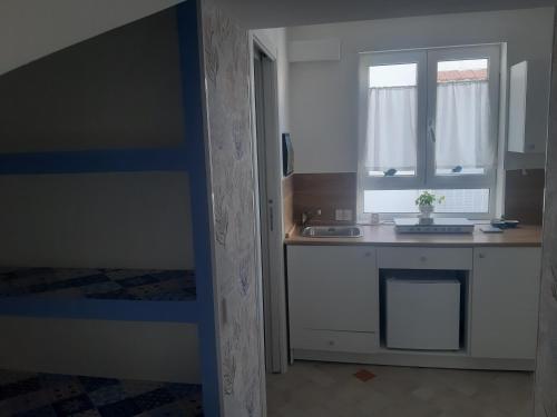 eine kleine Küche mit einem Waschbecken und einem Fenster in der Unterkunft coralinehome in Castellammare di Stabia