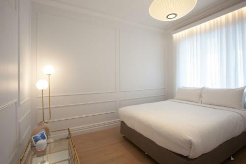 a white bedroom with a bed and a window at Bondi Casa del Sol in Sydney