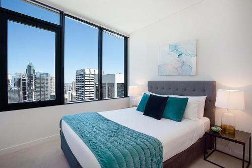 a bedroom with a large bed and large windows at City High in Sydney
