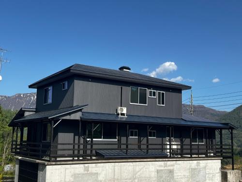 a black house on top of a building at Crows Nest Norikura by JAMSZ ROYALE in Otari