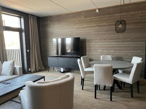a living room with a table and chairs and a television at Trysil Alpine Lodge in Trysil