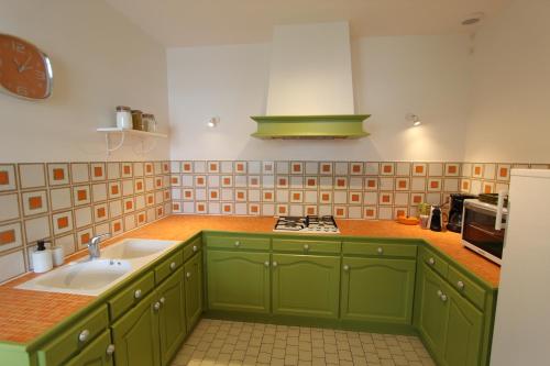 une cuisine avec des armoires vertes et un évier dans l'établissement 8 couchages à 6 klm des plages, à Saint-Denis-du-Payré