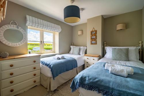 a bedroom with two beds and a window at Goose Cottage by Big Skies Cottages in Titchwell