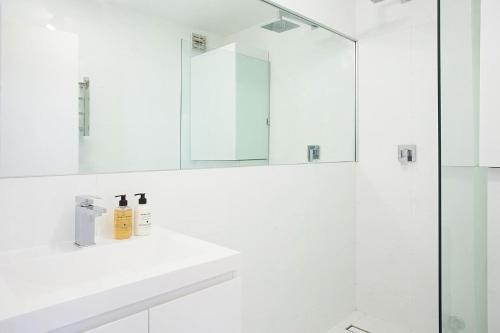 a white bathroom with a sink and a mirror at Centennial Retreat in Sydney