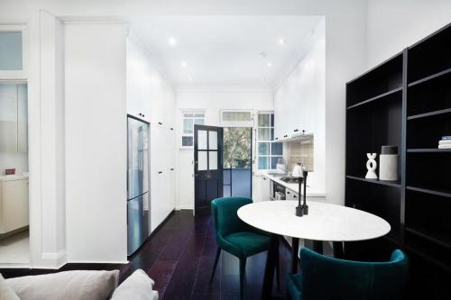 a kitchen and living room with a table and green chairs at Woollahra Contemporary in Sydney