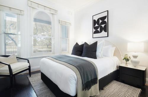 a white bedroom with a large bed and a chair at Woollahra Contemporary in Sydney