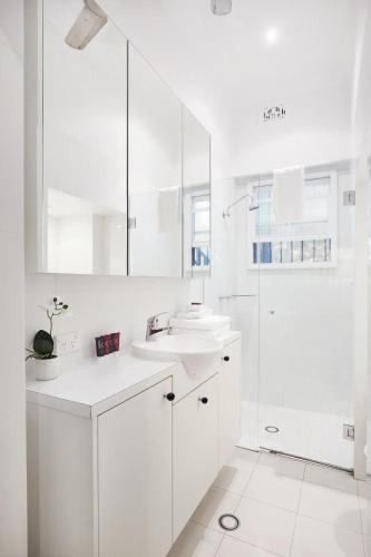 a white bathroom with a sink and a shower at Woollahra Contemporary in Sydney