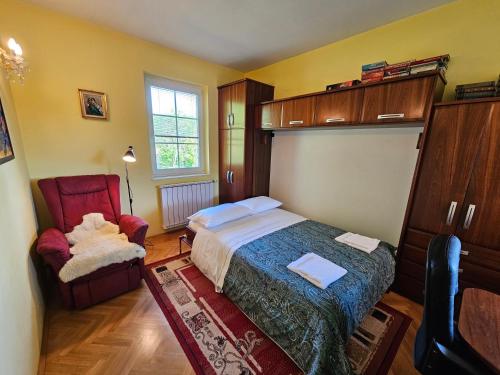 apartment AURORA في روغاسكا سلاتينا: غرفة نوم بسرير وكرسي احمر