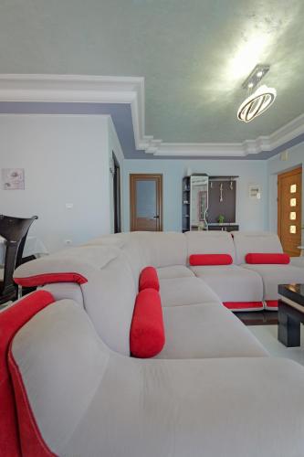a living room with a white couch with red pillows at Vila Nanaj in Sarandë
