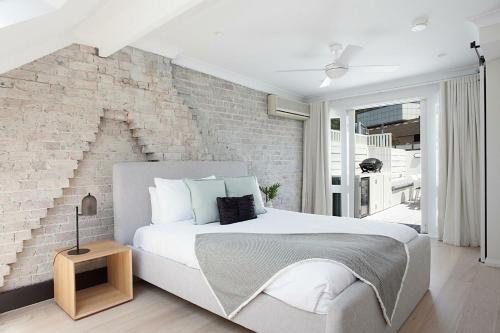 a bedroom with a white bed and a brick wall at Wharf House Woolloomooloo in Sydney