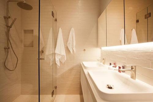 a white bathroom with two sinks and a shower at Wharf House Woolloomooloo in Sydney