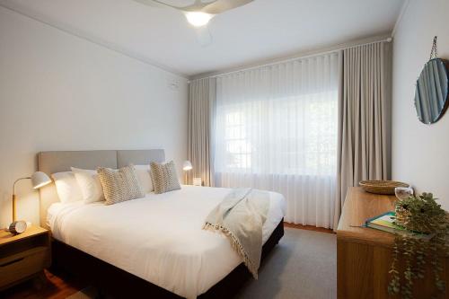 a bedroom with a large white bed and a window at Coastal Calm Coogee in Sydney
