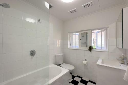 een witte badkamer met een toilet en een wastafel bij Coastal Calm Coogee in Sydney