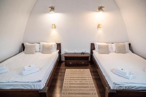 two beds in a room with white sheets at Hunnia - Huntanya in Vlăhiţa