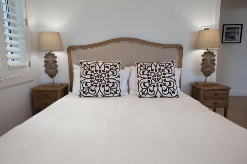 a bedroom with a white bed with two pillows at Villa Bianca Clovelly in Sydney