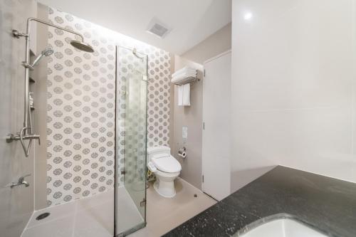 a bathroom with a toilet and a glass shower at Altera Hotel and Residence by At Mind in Pattaya Central