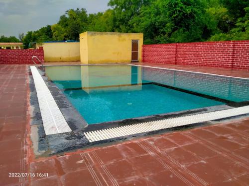 a swimming pool with blue water and a red wall at Vacation Village Camps - A Unit Of Braham Vatika Resort in Pushkar