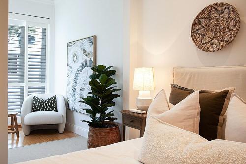 um quarto com uma cama, uma cadeira e uma planta em Chelsea Chic Paddington em Sydney