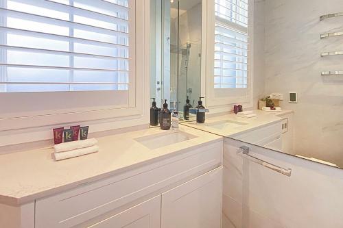 uma casa de banho branca com um lavatório e um espelho em Chelsea Chic Paddington em Sydney