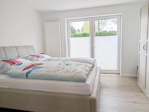 a white bedroom with a bed and two windows at Ferienwohnung Emilia in Garding