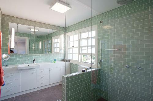 baño de azulejos verdes con lavabo y ducha en Colourful Coogee en Sídney
