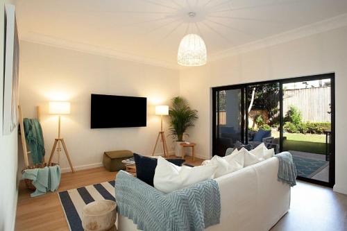 a living room with a white couch and a tv at Coastal Tamarama in Sydney