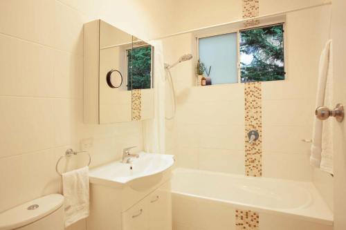 a bathroom with a sink and a tub and a toilet at Coogee Rest in Sydney