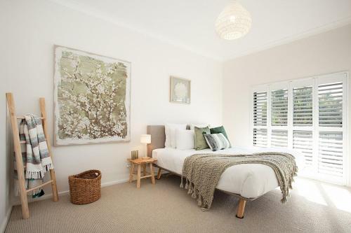 a white bedroom with a bed with a blanket on it at Coastal Tamarama in Sydney