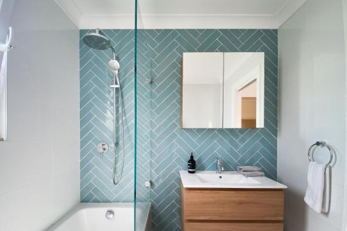 a bathroom with a shower and a sink and a mirror at Garden Oasis Sydenham in Sydney