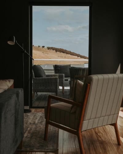 a living room with a chair and a view of a beach at Tranmere Seaside Serenity in Tranmere