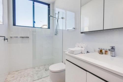 y baño blanco con aseo y ducha. en Coogee Bay Penthouse, en Sídney