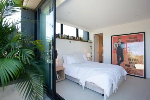 um quarto com uma cama branca e uma grande janela em The Treehouse Penthouse em Sydney