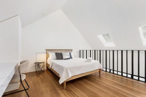 een witte slaapkamer met een bed en een zwarte leuning bij The Loft in Sydney