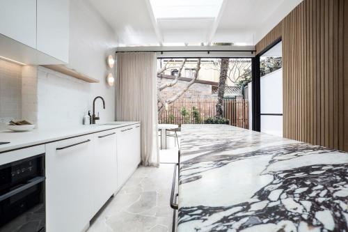 a kitchen with white cabinets and a marble counter top at The Timeless Modern Glebe in Sydney