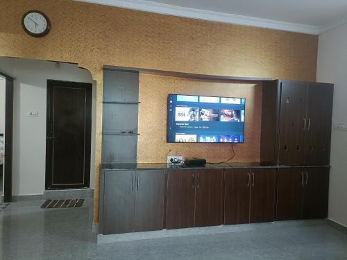 uma sala de estar com uma televisão na parede e um relógio em SREENIVASA HOME STAY em Tirupati