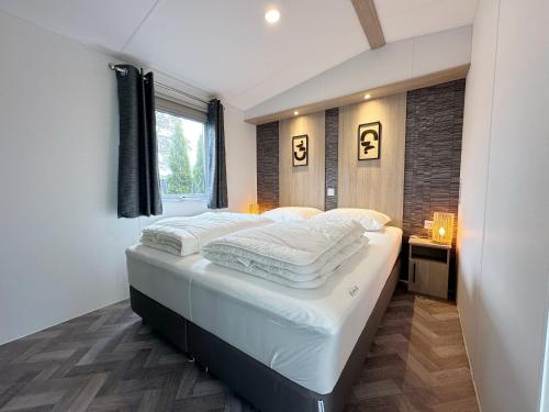 a bedroom with a bed with white sheets and a window at Chalet 531a op Recreatiepark De Wielen in Sint Maarten