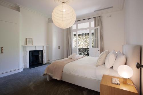 a white bedroom with a large bed and a chandelier at The Timeless Modern Glebe in Sydney
