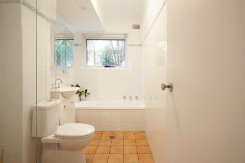 Baño blanco con aseo y lavamanos en La Brisa Coogee en Sídney