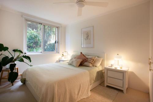 a white bedroom with a bed and two lamps at La Brisa Coogee in Sydney