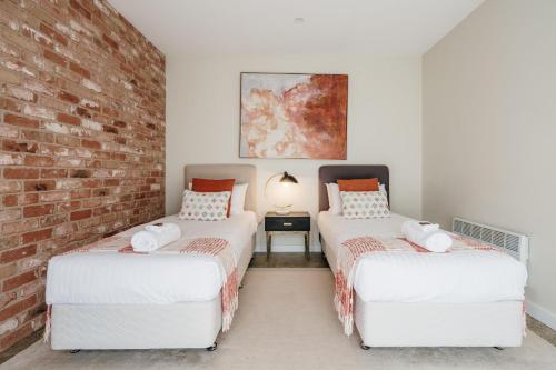 two beds in a room with a brick wall at Embracing Evandale in Evandale