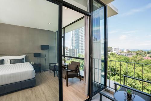 a bedroom with a bed and a view of a city at Altera Hotel and Residence by At Mind in Pattaya