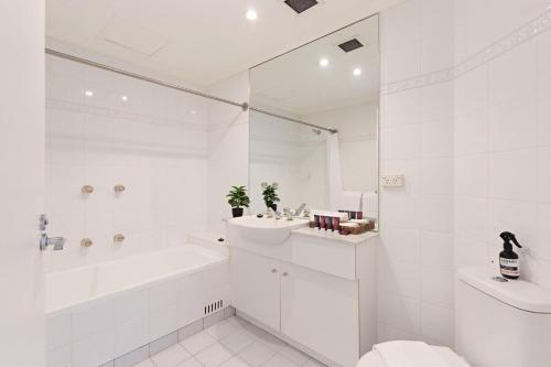 a white bathroom with a tub sink and a toilet at Palm Breeze in Coogee in Sydney
