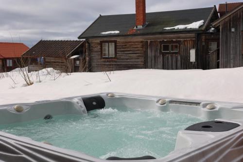 a hot tub in the snow in front of a house at Fryksas Chalet in Fryksås